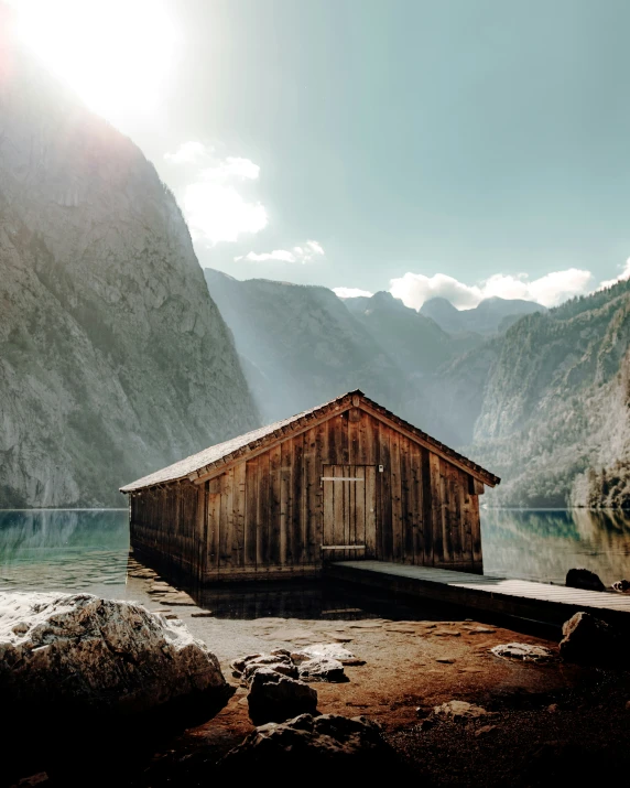 a small boathouse is surrounded by mountains