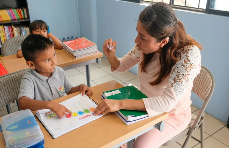 a child sitting in front of a woman in a class room