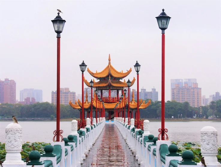 a view down a sidewalk of a small pagoda on the water