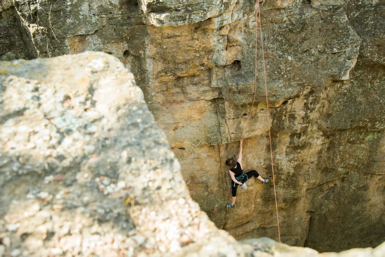 a climber ascending up a large rock face in the wilderness