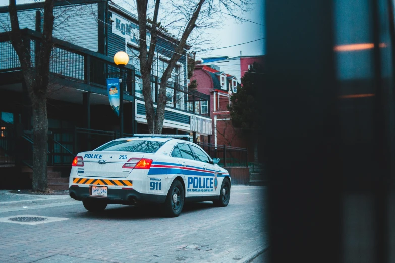 a police car driving down a street next to a lamp