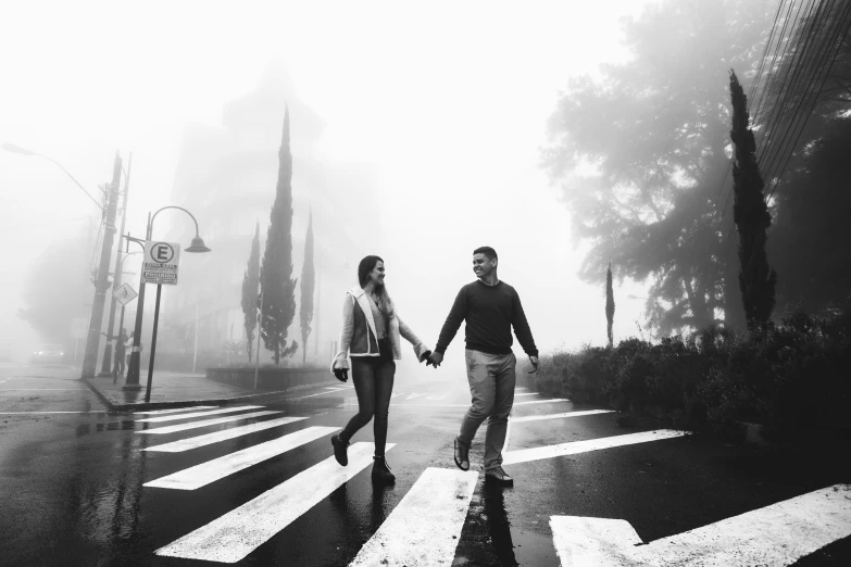 man and woman crossing road in the rain on a misty day