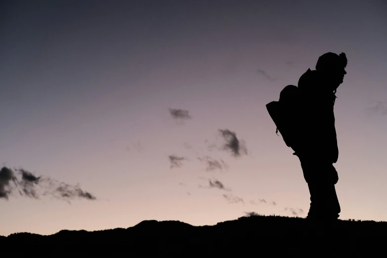 a person standing on top of a hill near a sunset