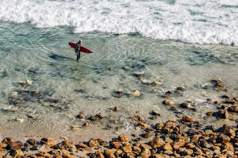 a person with a surf board standing in the ocean