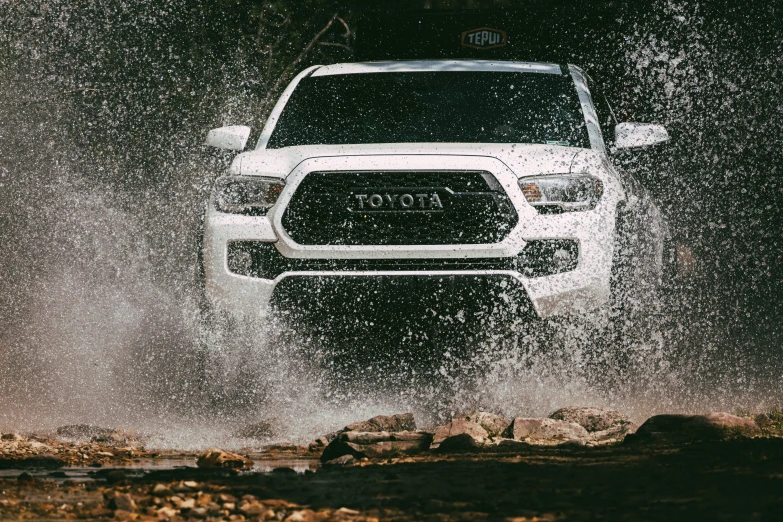 the front view of a white truck driving through water