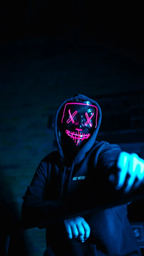 a man wearing a lit neon mask and a hooded sweatshirt