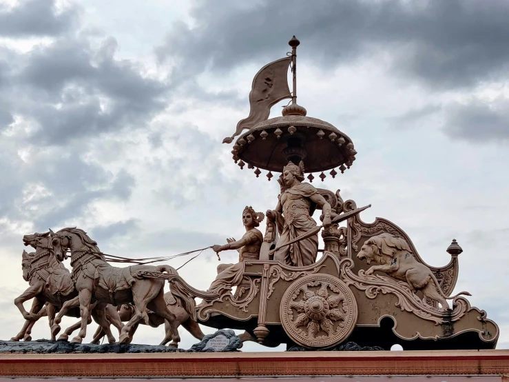 statues are sitting atop a stone structure under gray skies