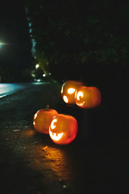 three carved pumpkins sitting outside in the dark