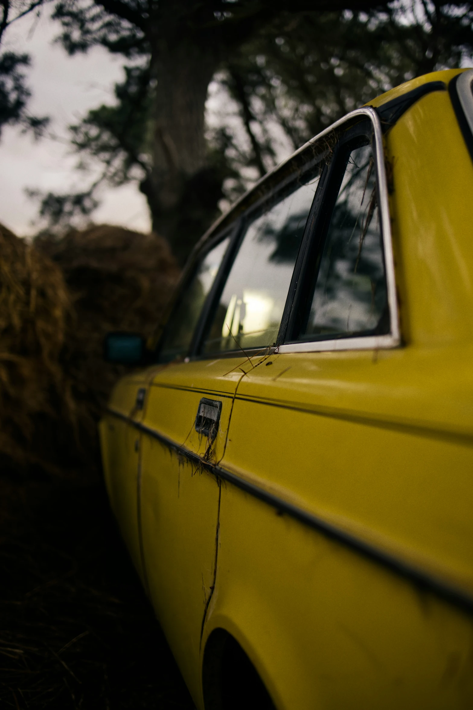 a yellow car parked in a grass field next to trees