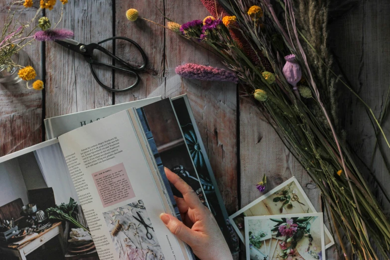 a person holding a flower that is on a book