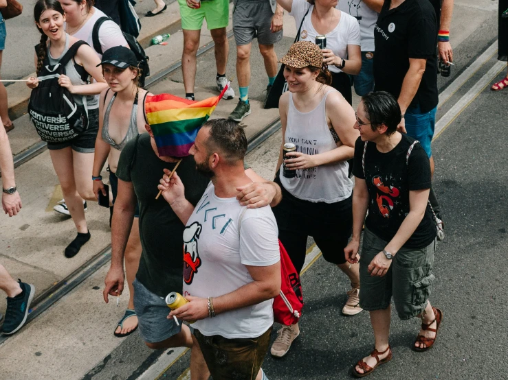 a man being hugged by a woman who is holding a rainbow flag