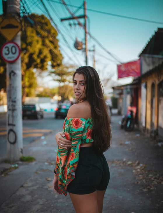 a woman poses in a green shorts and flowery top