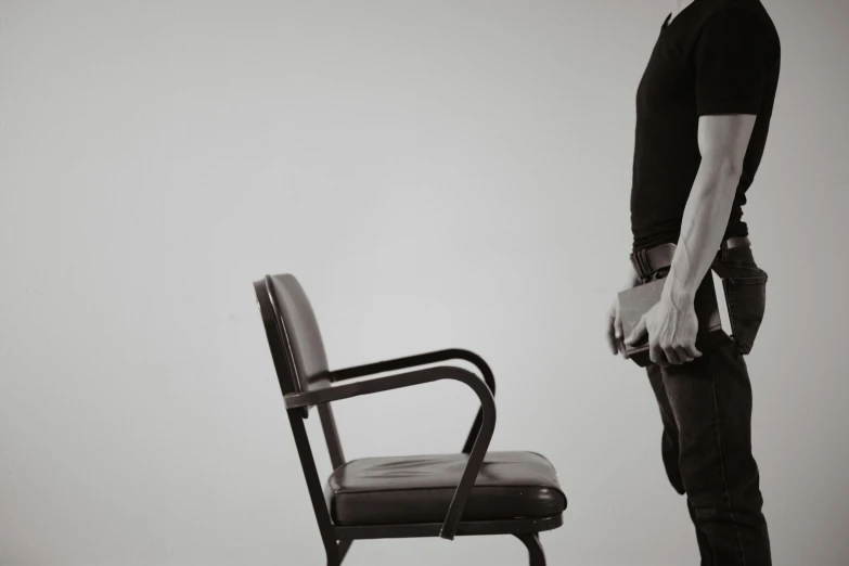 man stands by the black chair with his hand on it