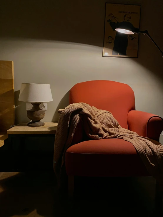 an orange chair and some books and lamp in a room