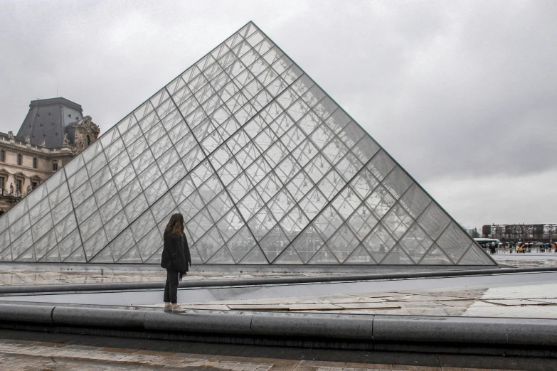 a woman stands in front of an outdoor pyramid