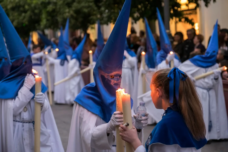 several woman dressed in blue holding a candle