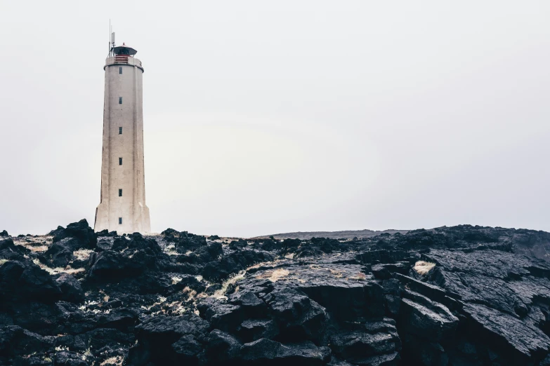 a white tower standing on top of a rocky hillside