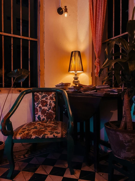 a living area with checkered carpet, a table with lamp and chairs