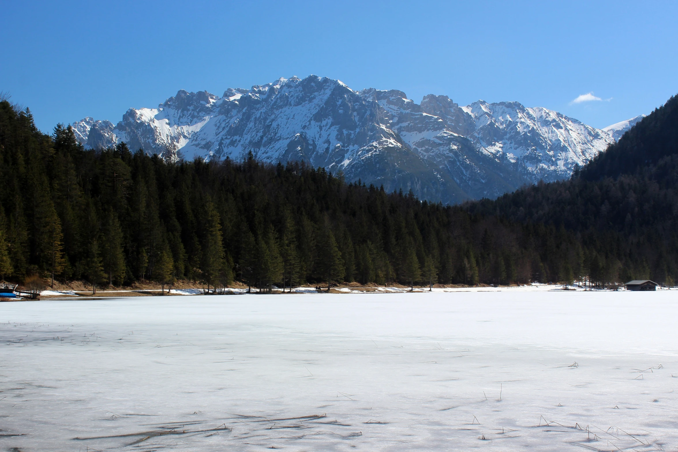 an empty field surrounded by snow covered mountains