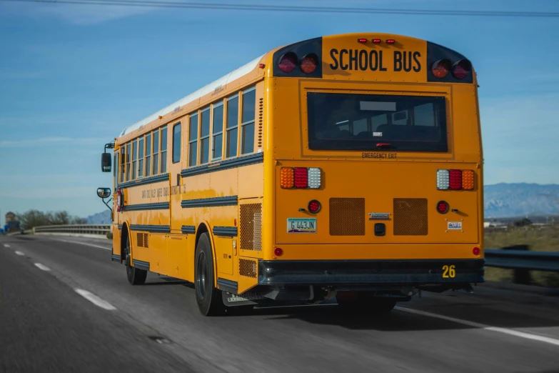 the back end of a school bus with a rear wing facing away from it on the road