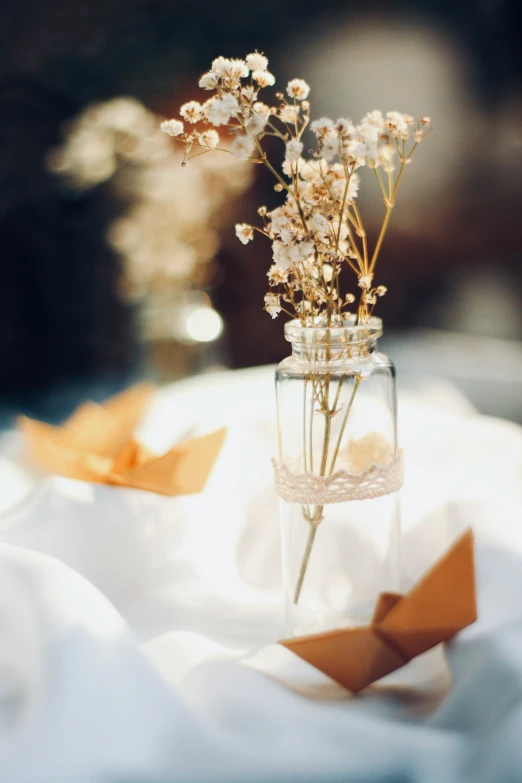 vase filled with baby's breath and orange paper floating in the air