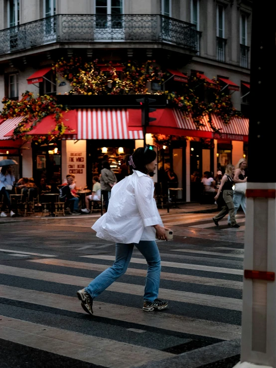 the girl walks across the road as people watch