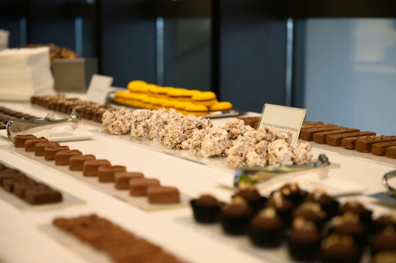 a long table filled with dessert items and trays of chocolate