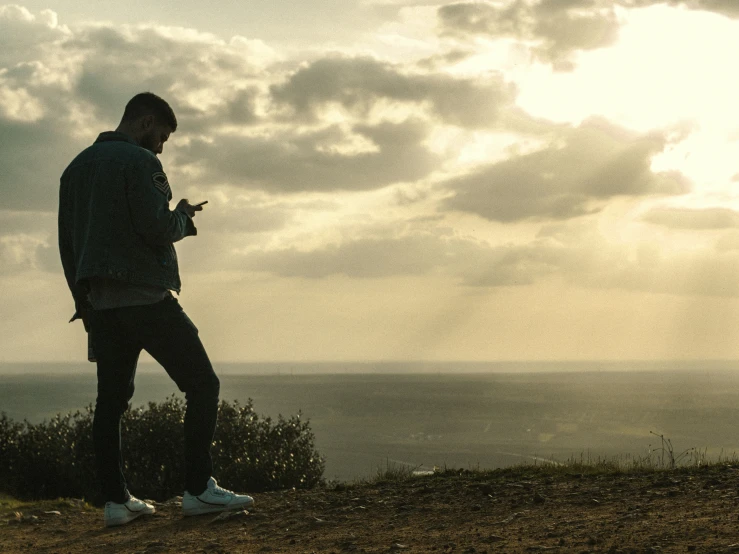 a man standing on top of a hill next to a forest