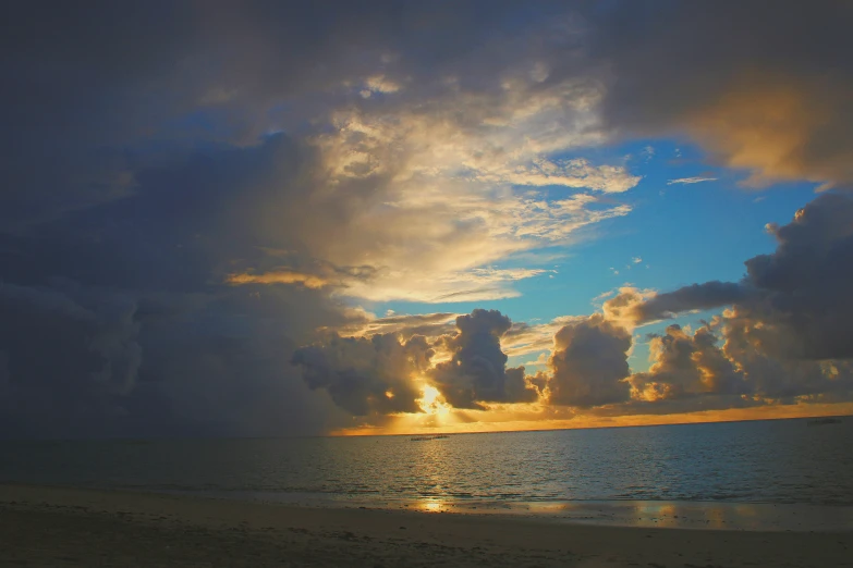 a sun shining through a cloud covered sky over the ocean