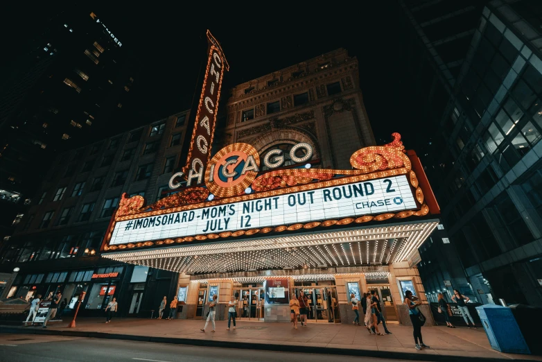 a theater sign with people walking by in the night