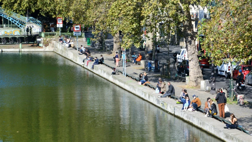 a crowd of people walking and riding bikes along side a river