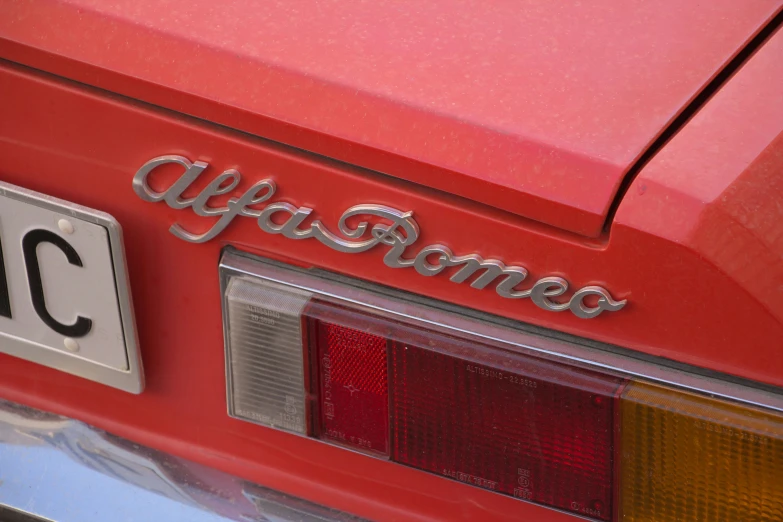 the front end of a red car with the word alfa - roma on it