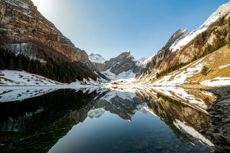 a mountain range with a lake reflecting the sky