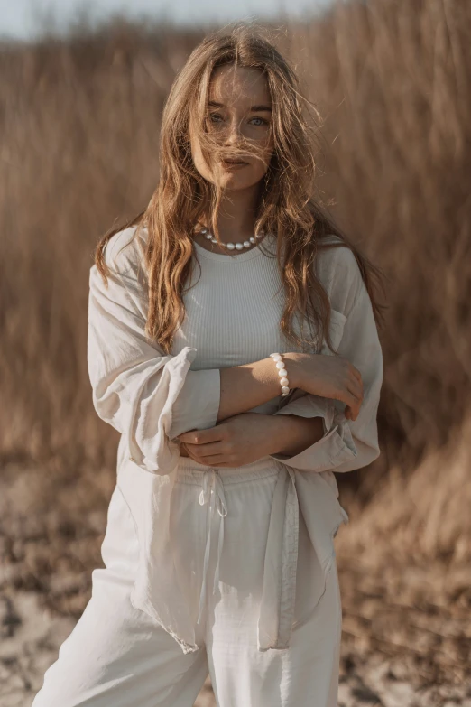 a woman standing in a white outfit with her arms crossed