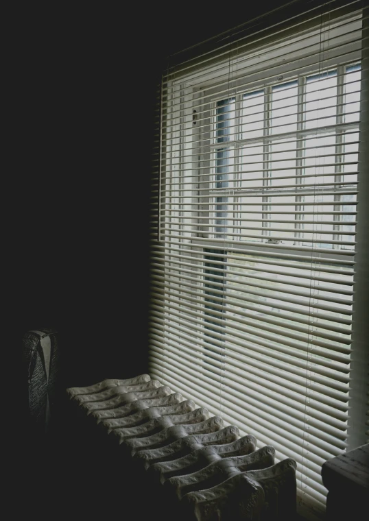 several sinks sit under a window with blinds in the dark