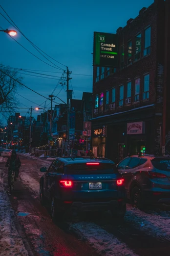 two cars parked on a snowy street with buildings