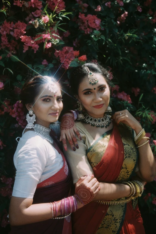 a pair of women pose in front of purple flowers