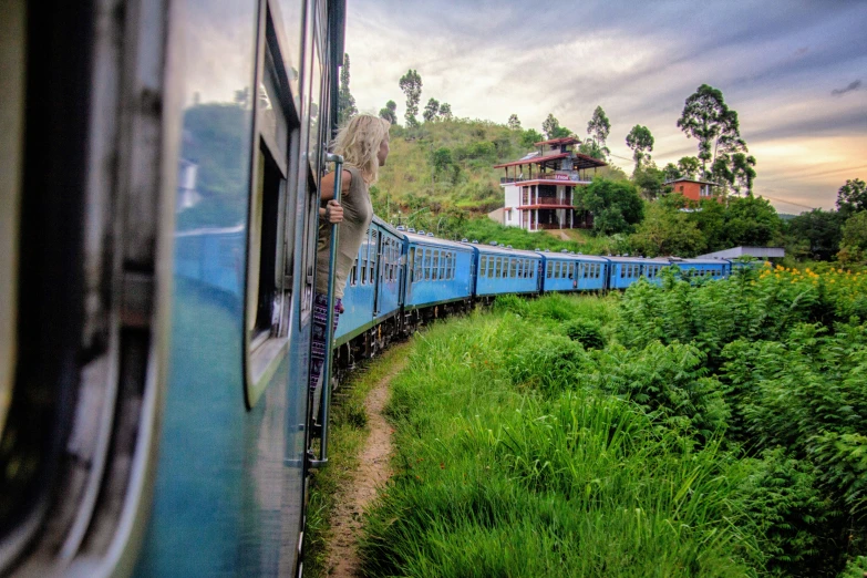 the blue passenger train is going through the countryside