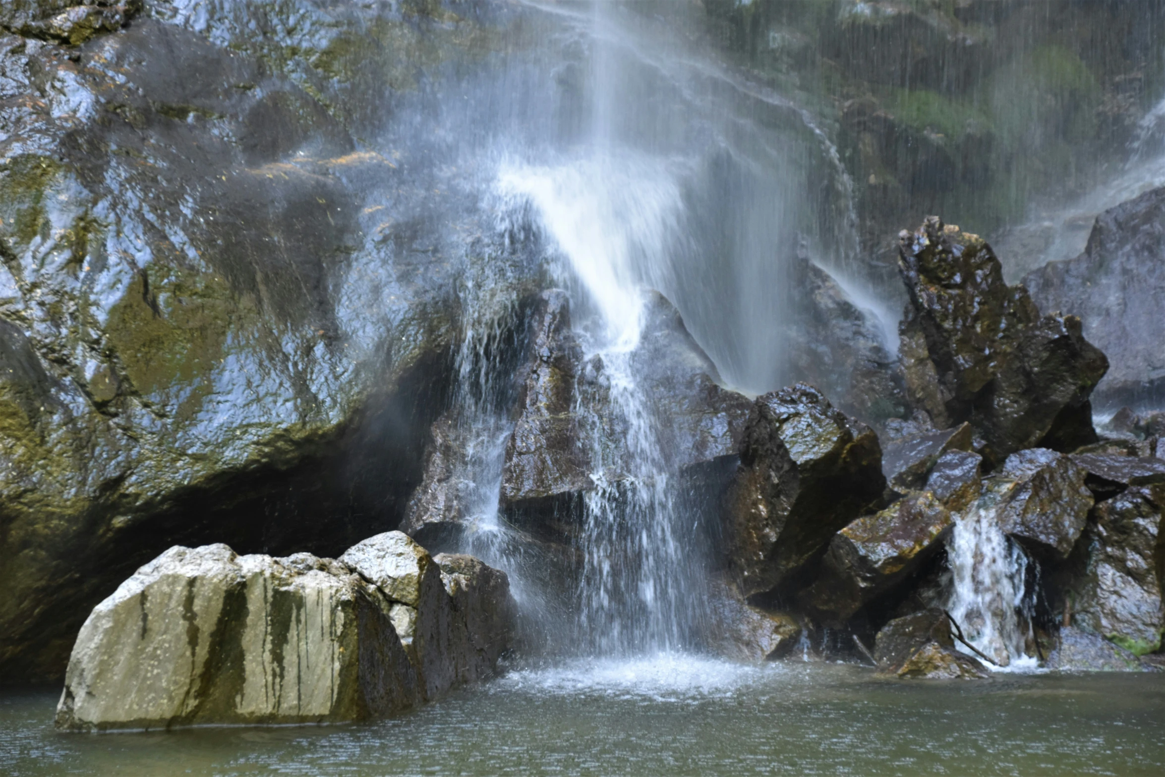 two large rocks sit in front of a waterfall