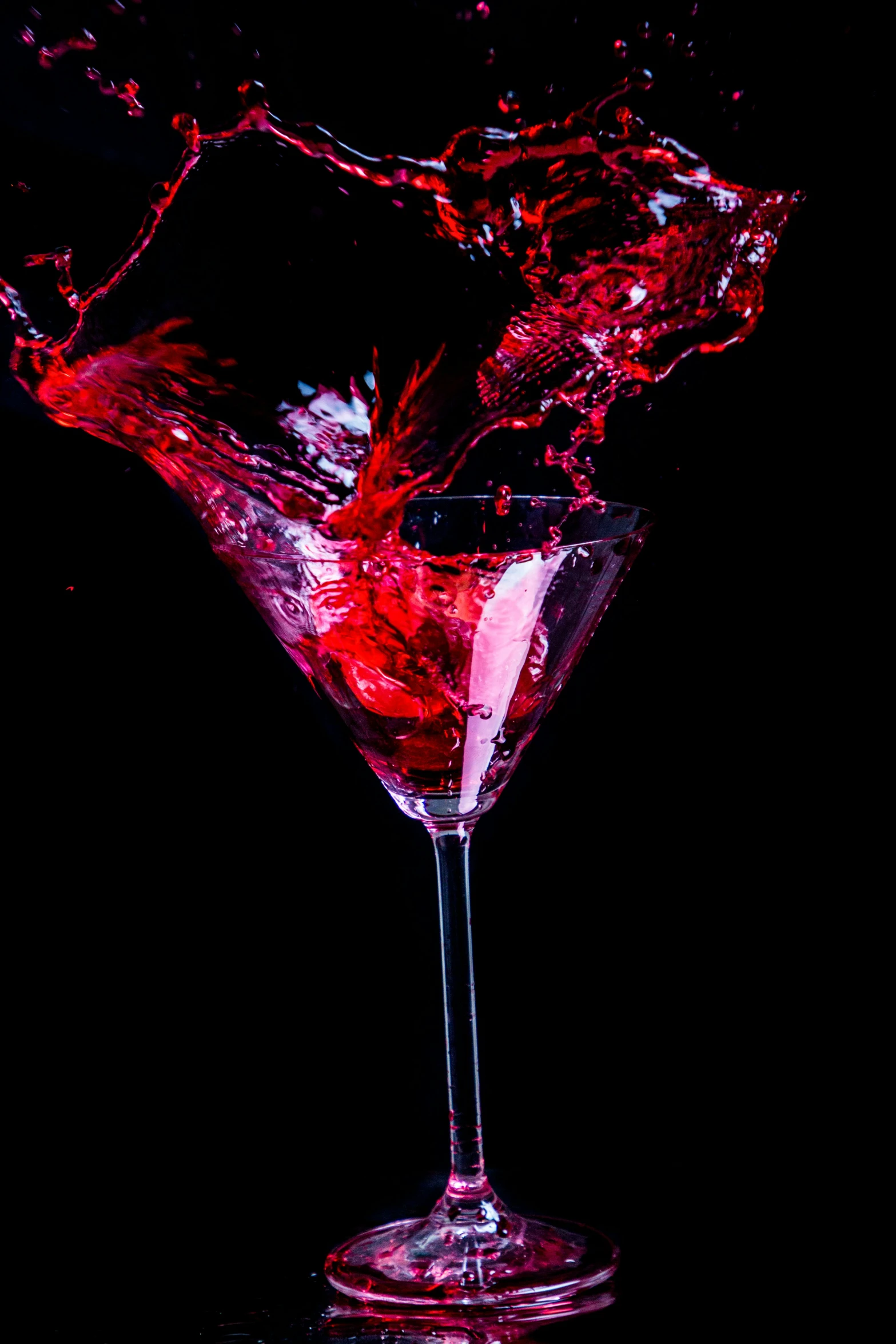 a red beverage splashing in to a martini glass