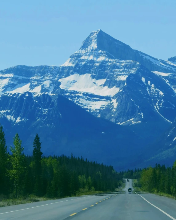 a road with snow capped mountains on the other side