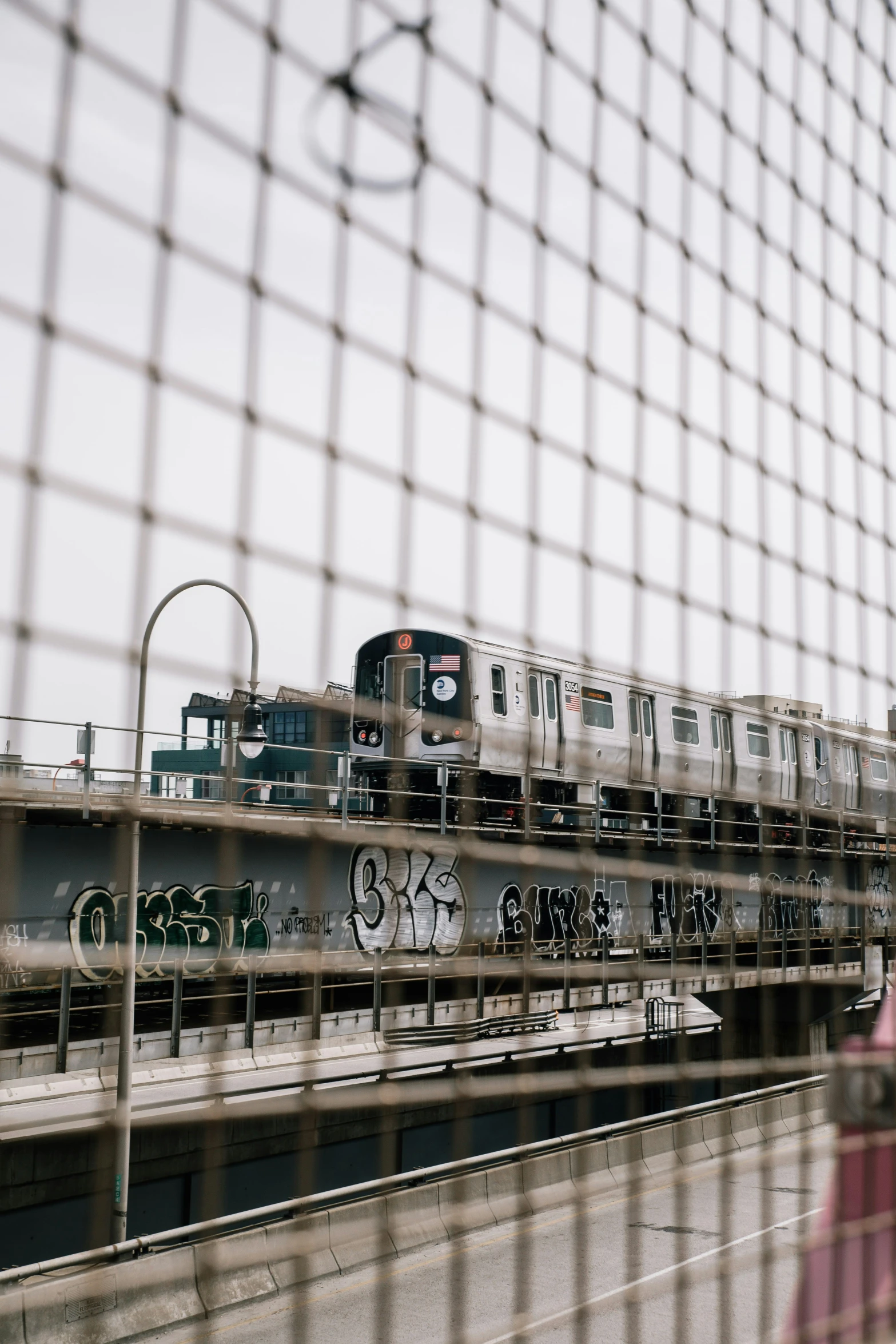 a train traveling on the tracks through a wire fence