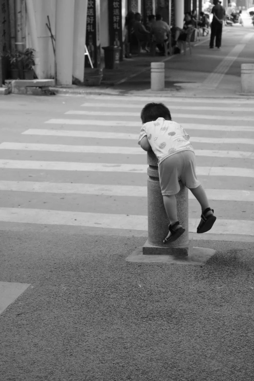 a boy is sleeping on a post by the street