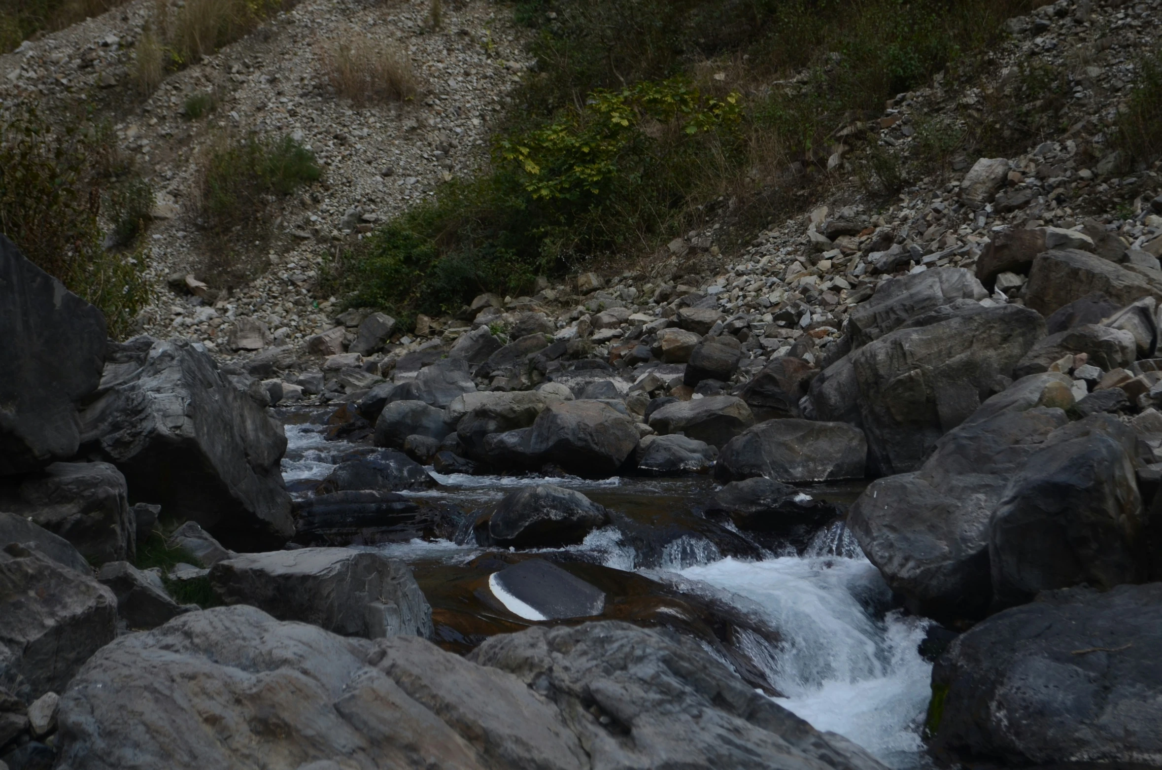 a man stands on a rocky hill near a stream