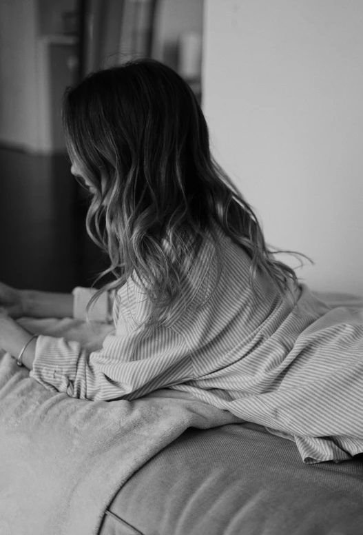 the woman is sitting on a couch with her leg in a pillow