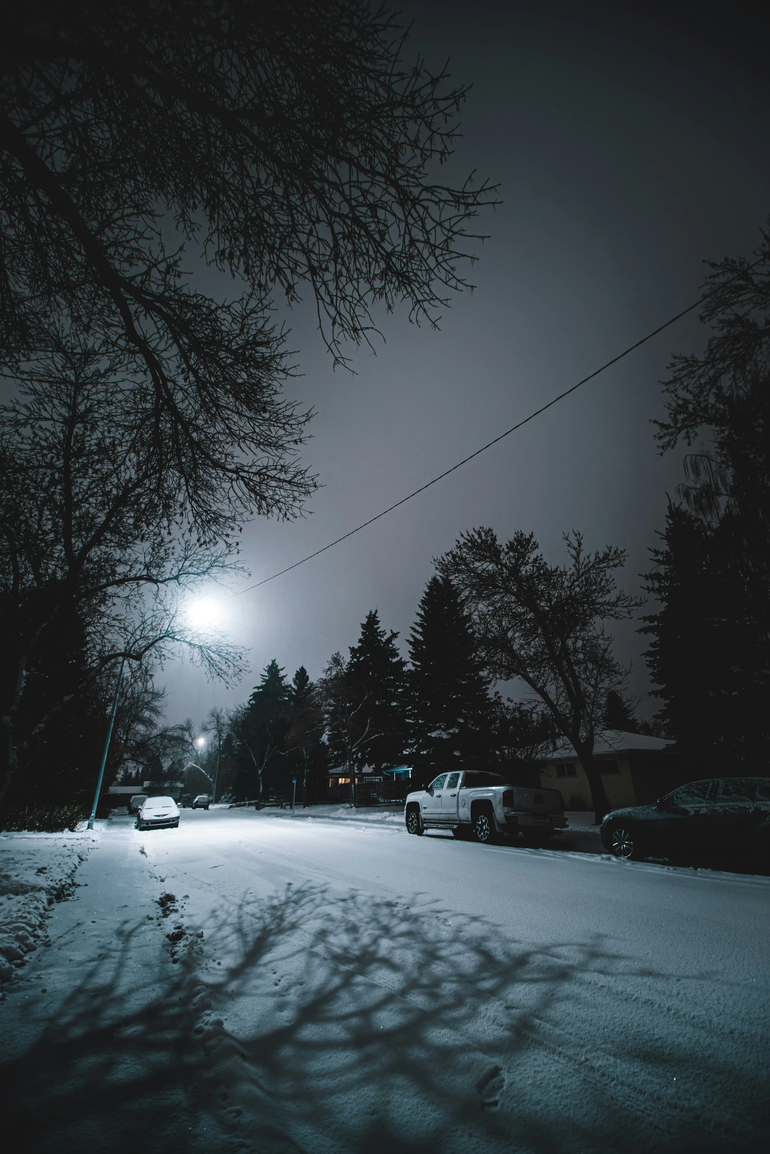 a snowy road with a lamp and trees