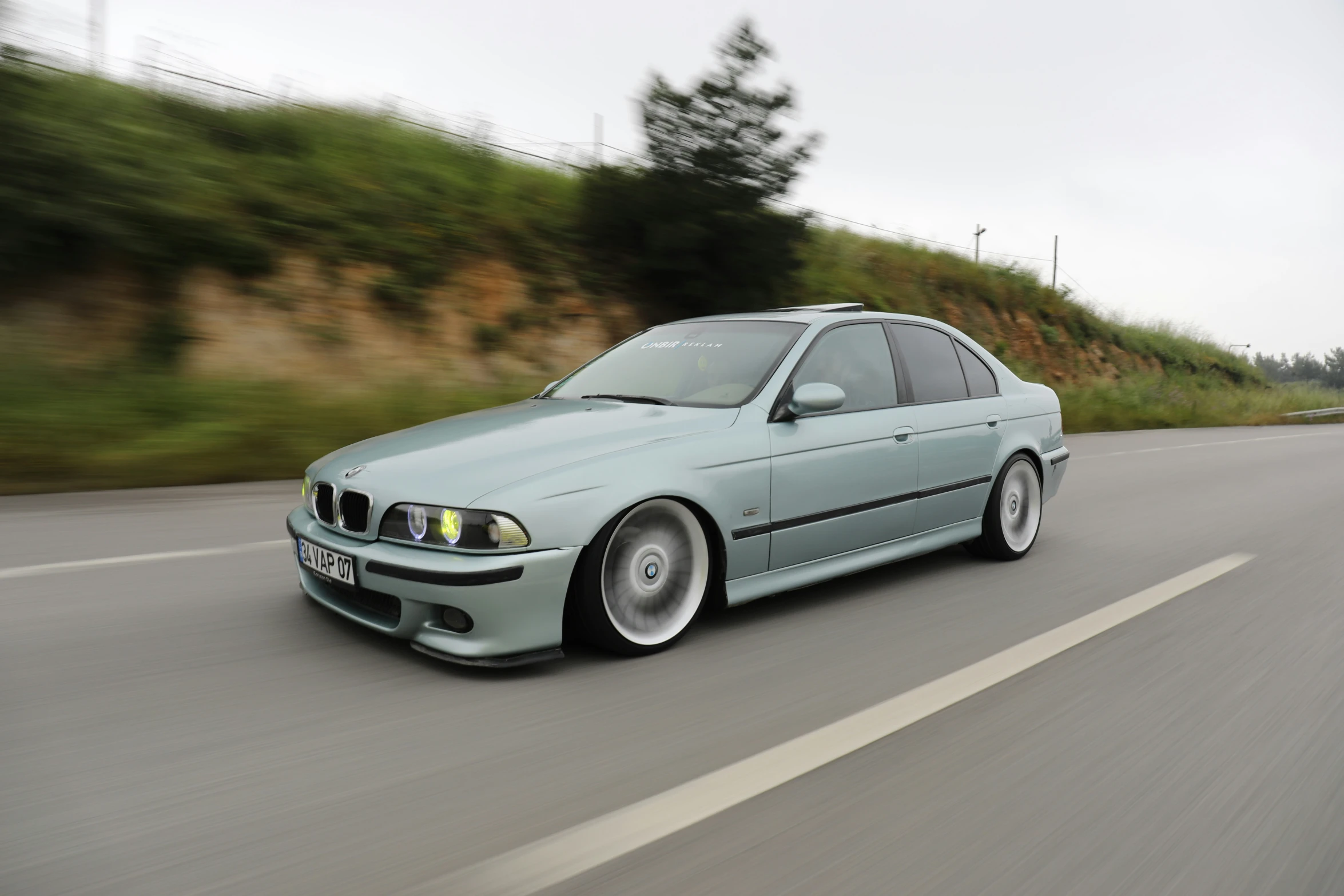 an artistic blue bmw car driving down the road