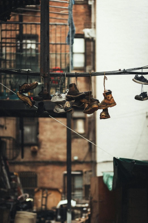 several pairs of shoes hang on a wire outside