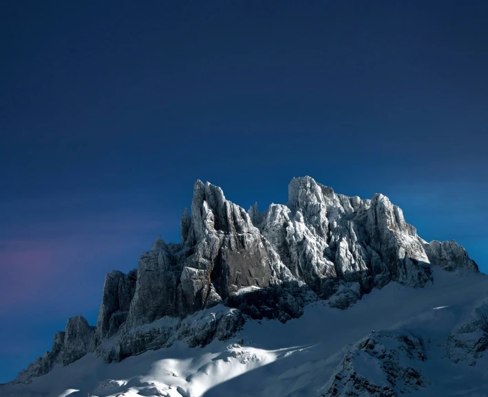 a snow covered mountain under a cloud filled sky