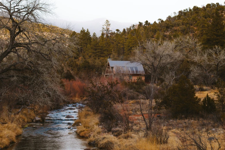 an old house sits next to a stream in the woods